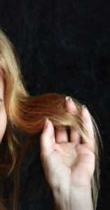 A female's hand caressing her blond hair.